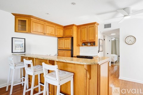 A kitchen with wooden cabinets and white chairs.