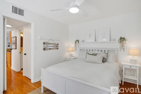 A bedroom with a white bed and a white ceiling fan.