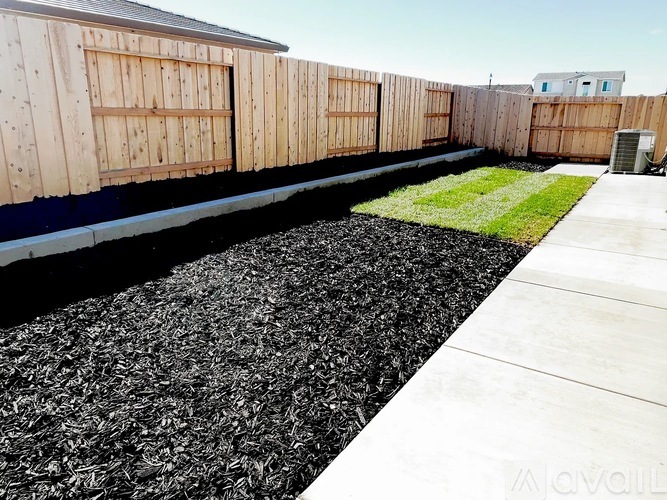 A train track with wooden fence and grassy area beside it.