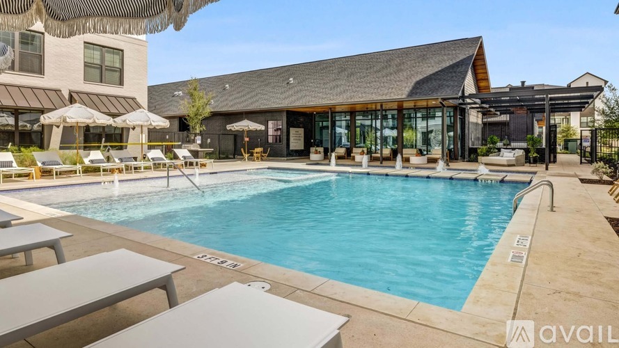 A large outdoor swimming pool with sun loungers and a building in the background.