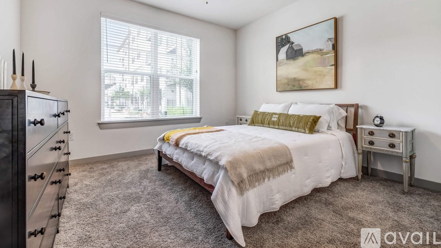 A bedroom with a large bed, a dresser, and a painting on the wall.
