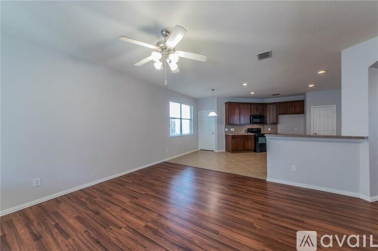 A spacious room with wooden flooring and a ceiling fan.