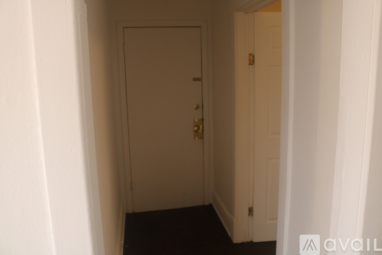 A white door with a gold handle is in a hallway.