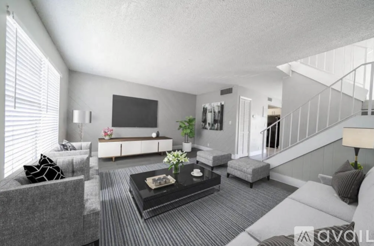 A living room with a grey couch, a black coffee table, and a television on the wall.