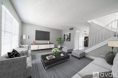 A living room with a grey couch, a black coffee table, and a television on the wall.