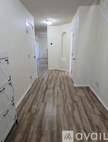 A hallway with wood flooring and white walls.