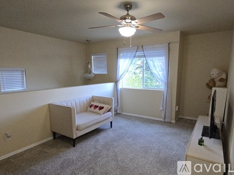 A living room with a white couch and a ceiling fan.
