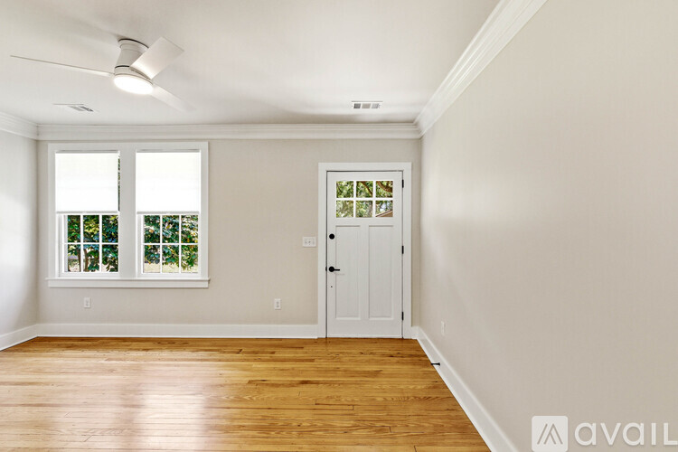 A room with a white door and a window with a view of trees.