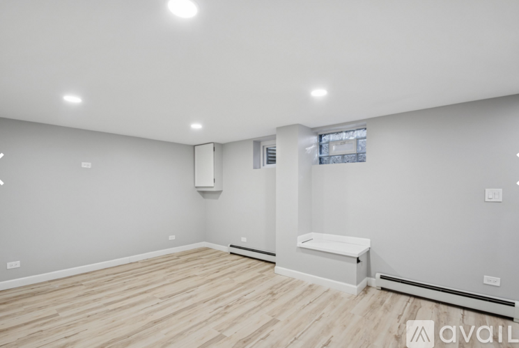 A spacious room with wooden flooring and white walls.
