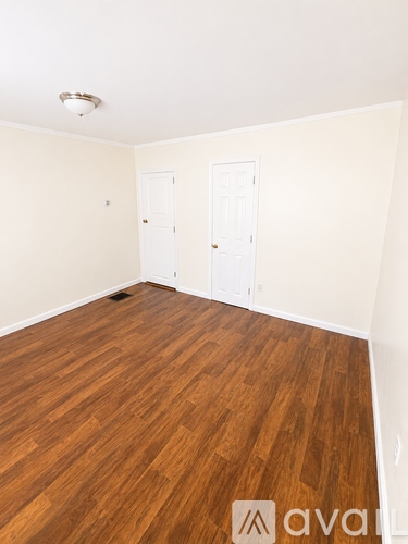 A room with wooden flooring and two white doors.