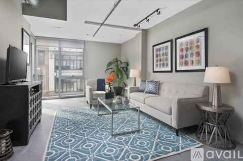 A living room with a grey couch, a glass coffee table, and a television.