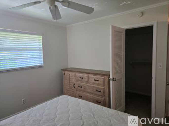 A bedroom with a bed, dresser, and a ceiling fan.