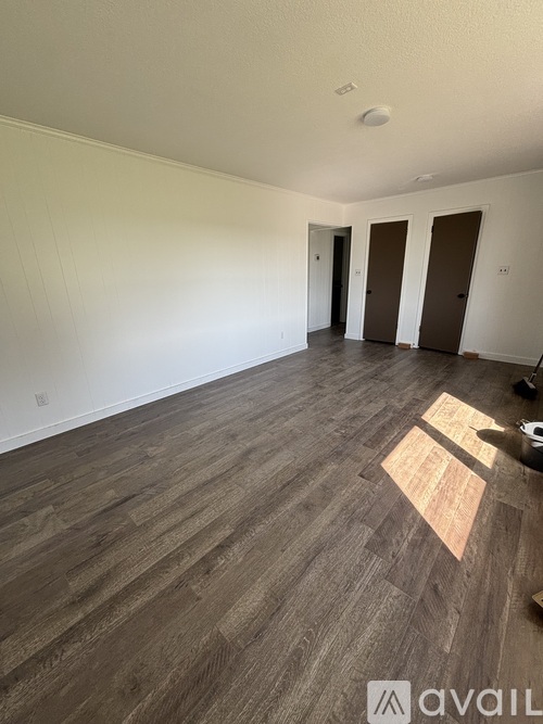 A room with wooden flooring and two doors.