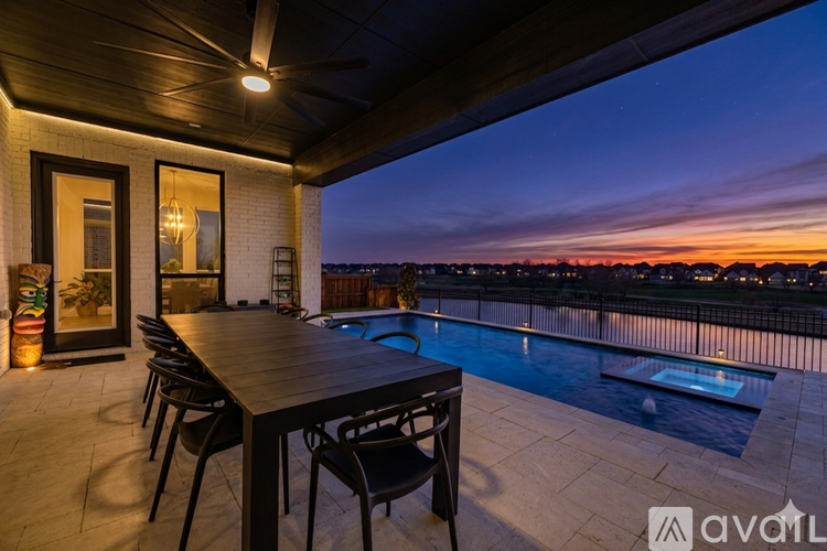 A table and chairs are set up on a balcony overlooking a pool.