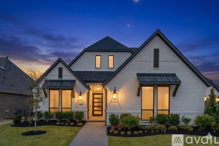 A modern house with a dark roof and a lit up entrance.