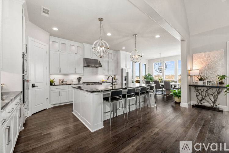 A modern kitchen with white cabinets and a dark wood floor.