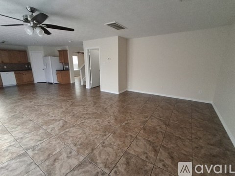 A spacious room with a ceiling fan and tile flooring.