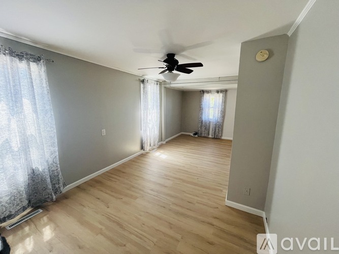 A room with a ceiling fan and wooden flooring.