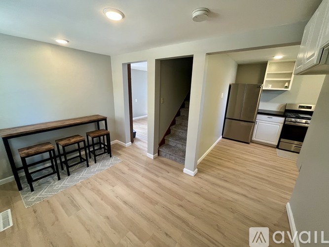 A kitchen area with a bar stool and a refrigerator.