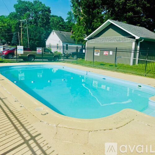 A small pool with a concrete edge and a metal fence around it.