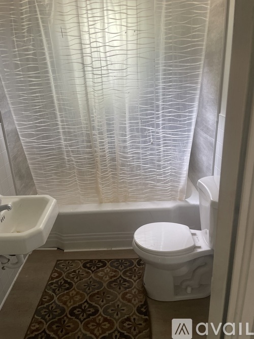 A white toilet in a bathroom with a patterned rug.