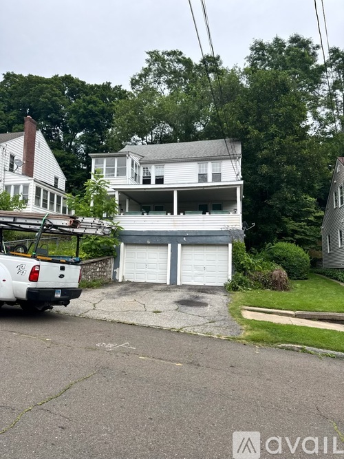 A white truck is parked in front of a two-story house.