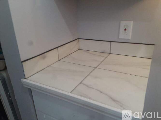 A white marble countertop with a light switch on the wall.