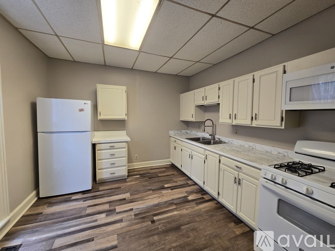 A kitchen with a white fridge, white cabinets, and a white stove.