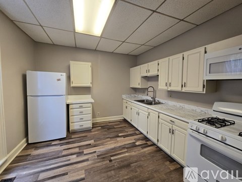 A kitchen with a white fridge, white cabinets, and a white stove.