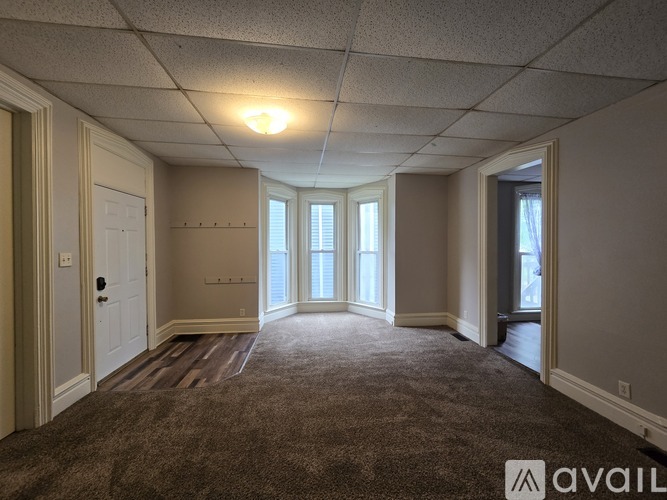 A spacious room with a carpeted floor and a door on the left side.