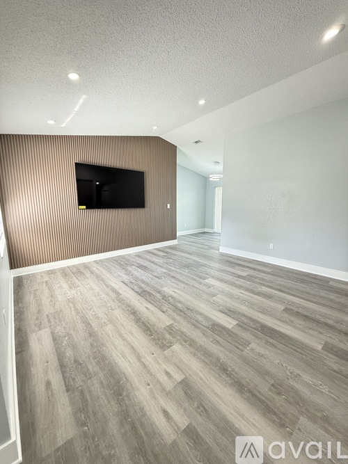 A room with a wooden floor and a flat screen TV mounted on the wall.