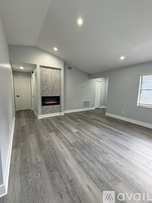 A spacious room with wood flooring and a fireplace.