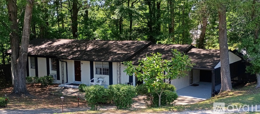 A house with a white exterior is surrounded by trees.