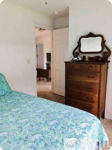 A bedroom with a bed, dresser and mirror.