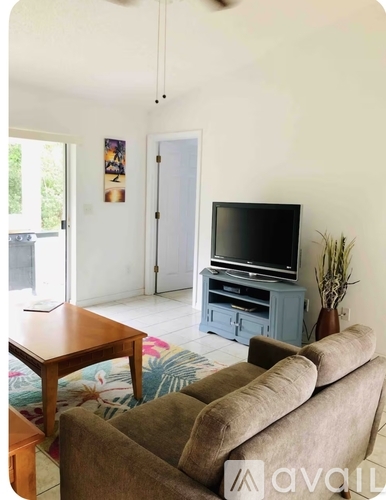 A living room with a brown couch, a wooden table, and a television on a cabinet.
