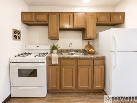 A kitchen with a white stove, wooden cabinets, and a white refrigerator.