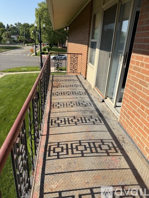 A brick building with a black railing and a tiled walkway.