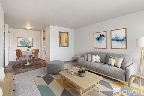 A living room with a grey couch, a coffee table, and a dining table with chairs.