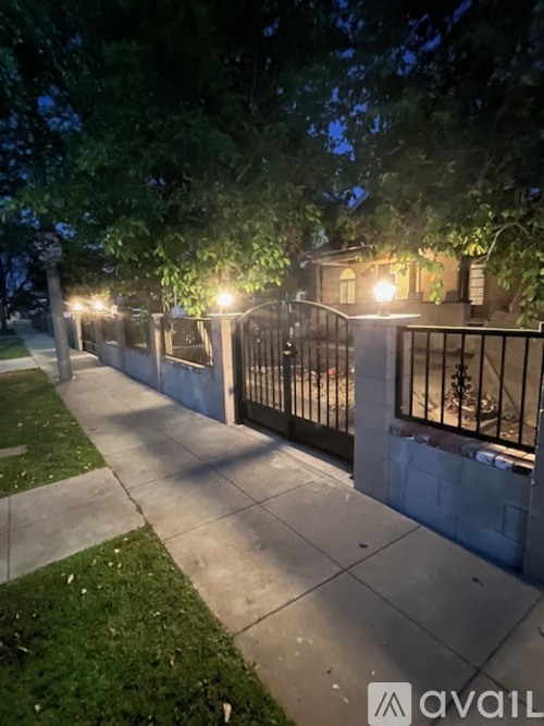 A sidewalk with a metal fence and a house in the background.