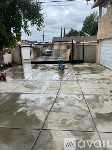 A wet driveway with a robotic pool cleaner in the middle.