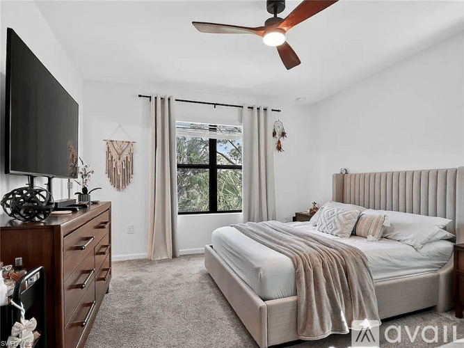 A bedroom with a large bed, a television, and a ceiling fan.