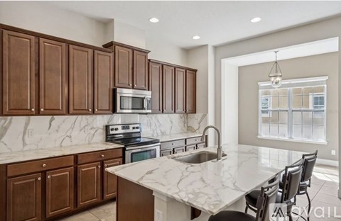 A kitchen with brown cabinets and a marble countertop.