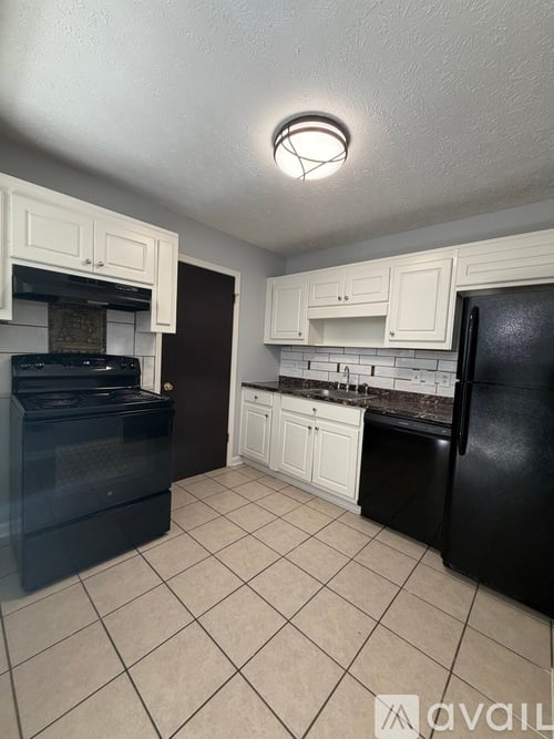 A kitchen with black appliances and white cabinets.