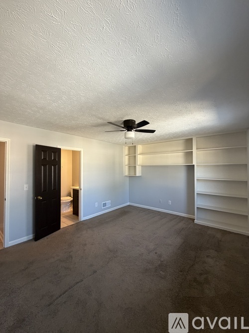 A room with a ceiling fan and a door leading to another room.