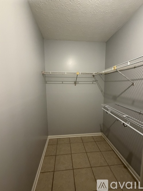 Empty walk-in closet with shelves and tiled floor.