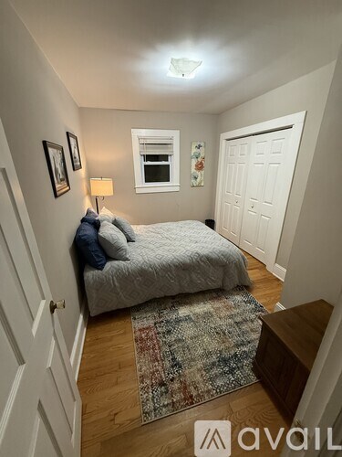 A bedroom with a bed, a lamp, a rug and a window.