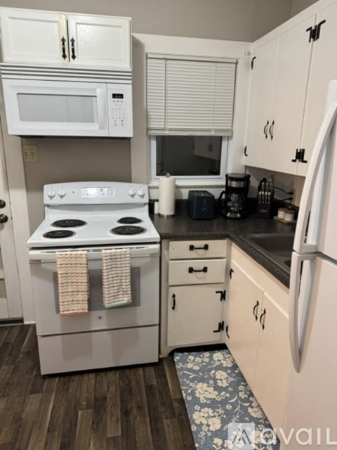 A white stove with a towel on it is in a kitchen with white cabinets.