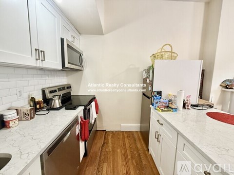 A kitchen with white cabinets and a white fridge.