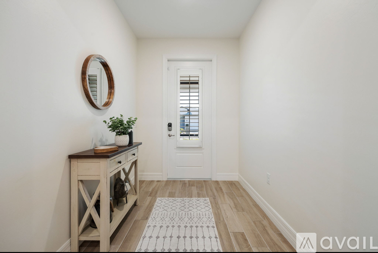A hallway with a wooden table and a mirror on the wall.