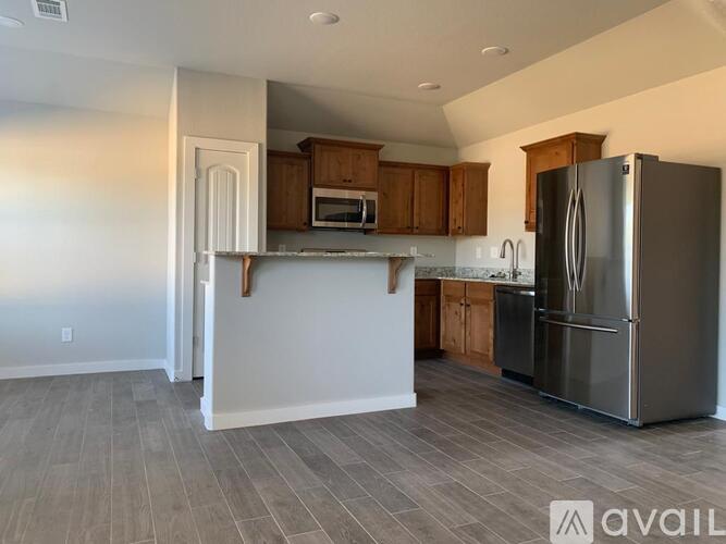 A kitchen with a refrigerator, microwave, and cabinets.